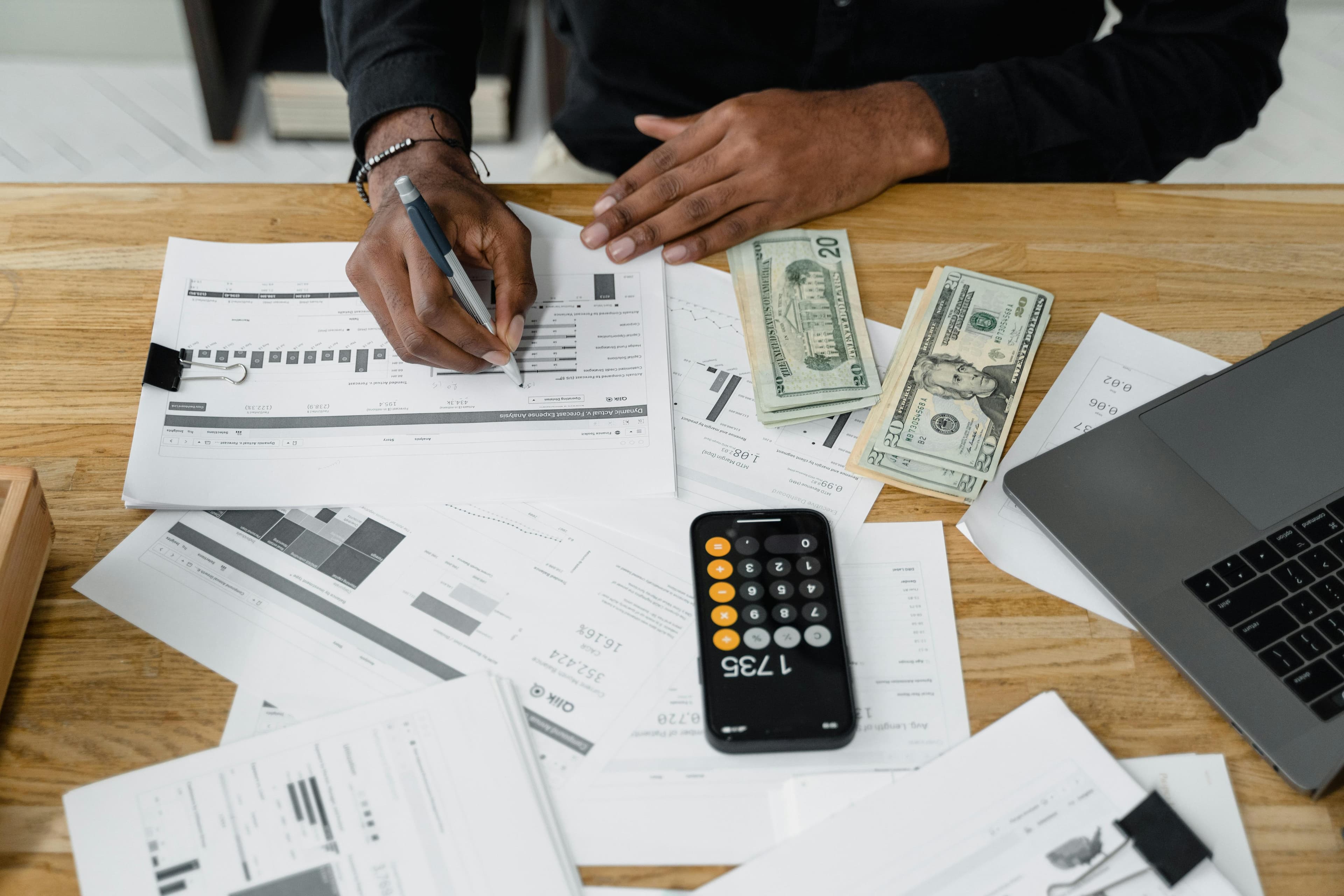 Accounting workspace with paperwork, calculator, laptop, and invoice planning documents